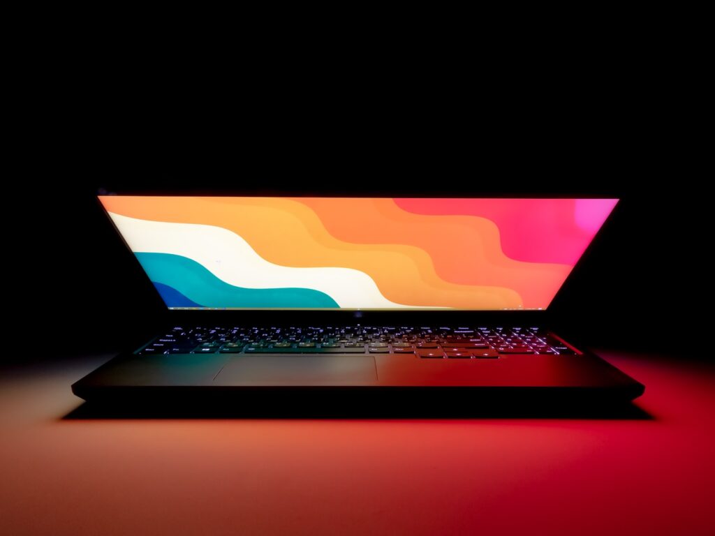 A black laptop on a white table in a dark room